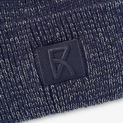 Närbild på den broderade loggan på den marinblå mössan.
