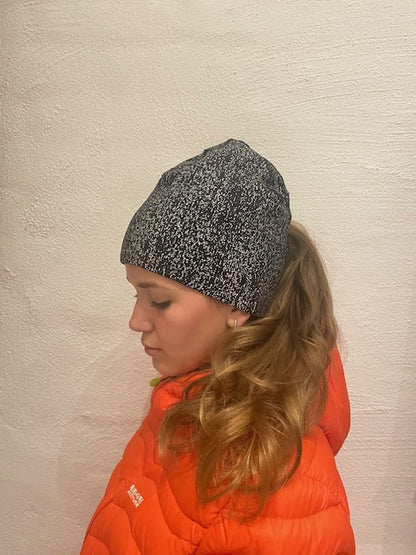 Svart reflexmössa i Coolmax® med reflexdetaljer och hål för hästsvans, bild på modell.