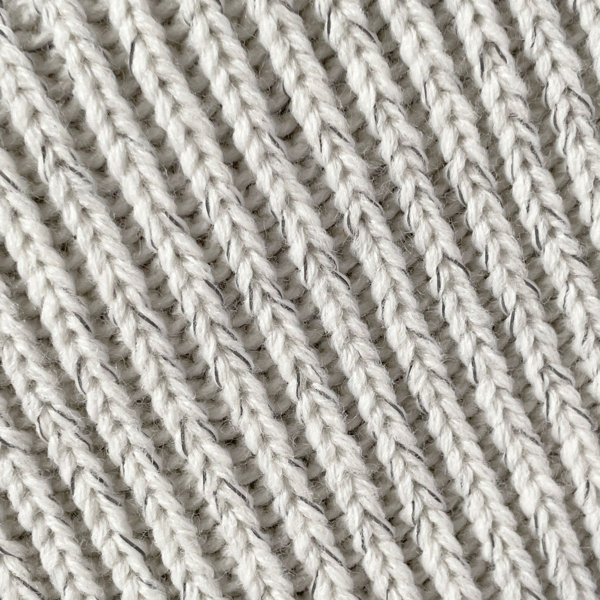 Närbild på reflexgarnet i den beige mössan.