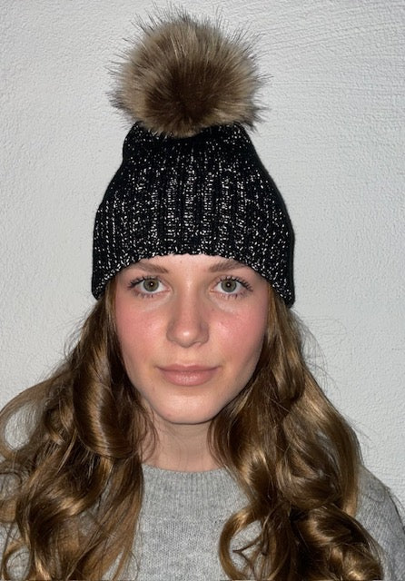 Bild på den svarta ribbstickade mössan på modell och reflextrådar som lyser.
