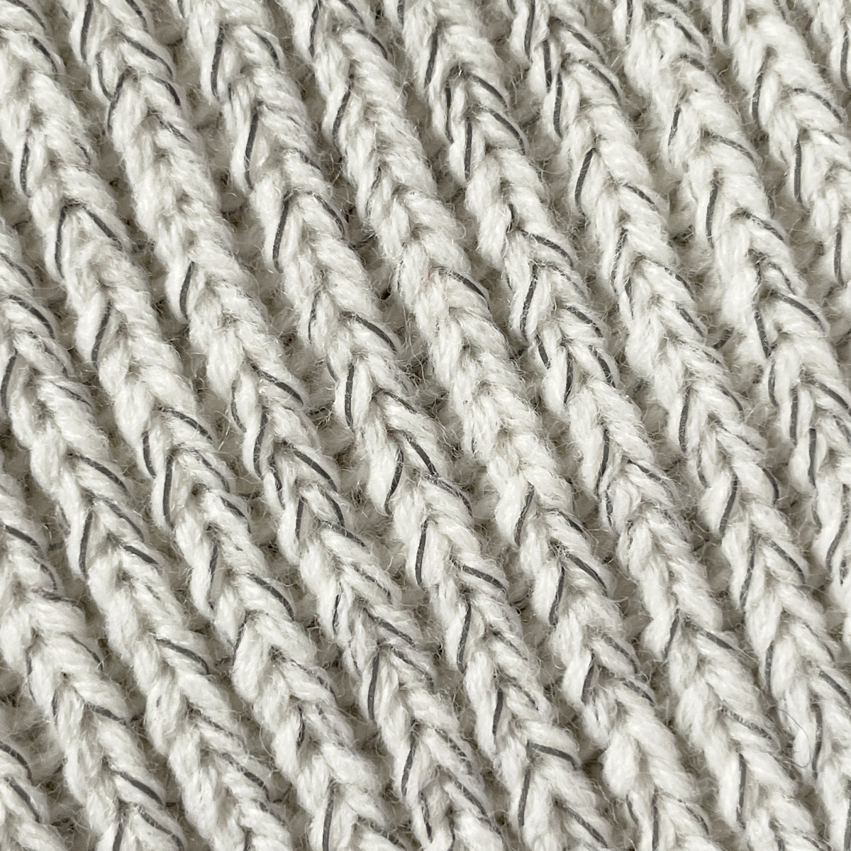 Närbild på reflextrådarna och materialet i det beige reflexpannbandet.